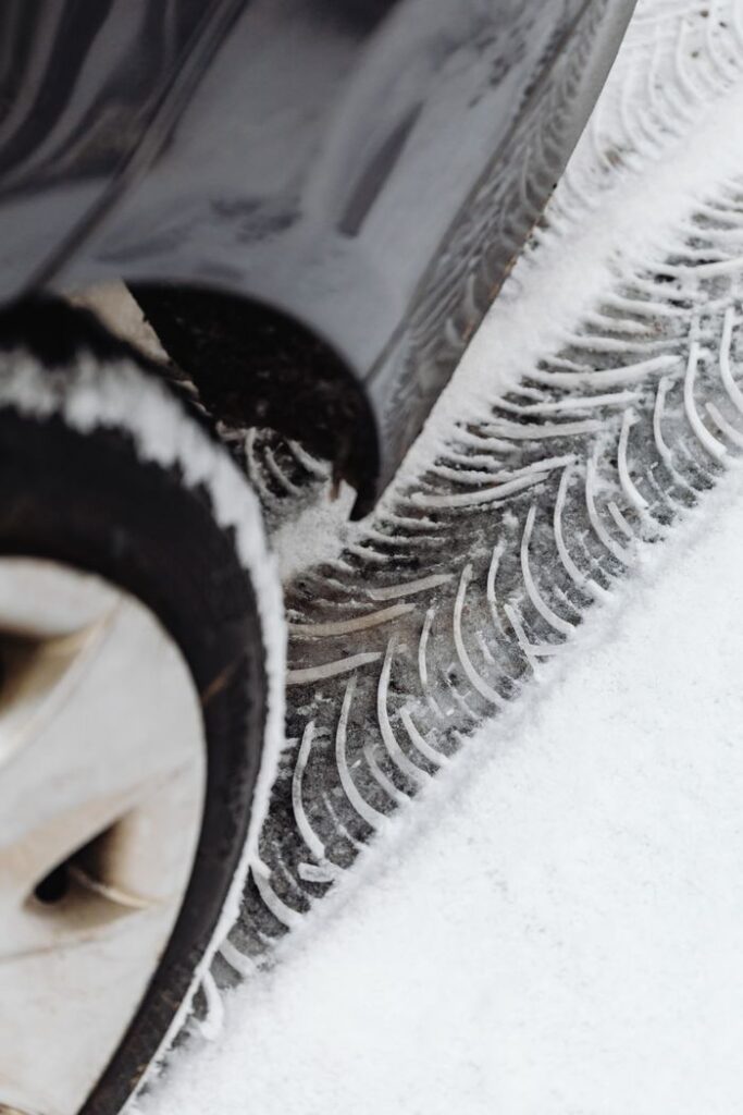 Detailed view of car tire and tracks on snowy ground highlighting winter conditions.